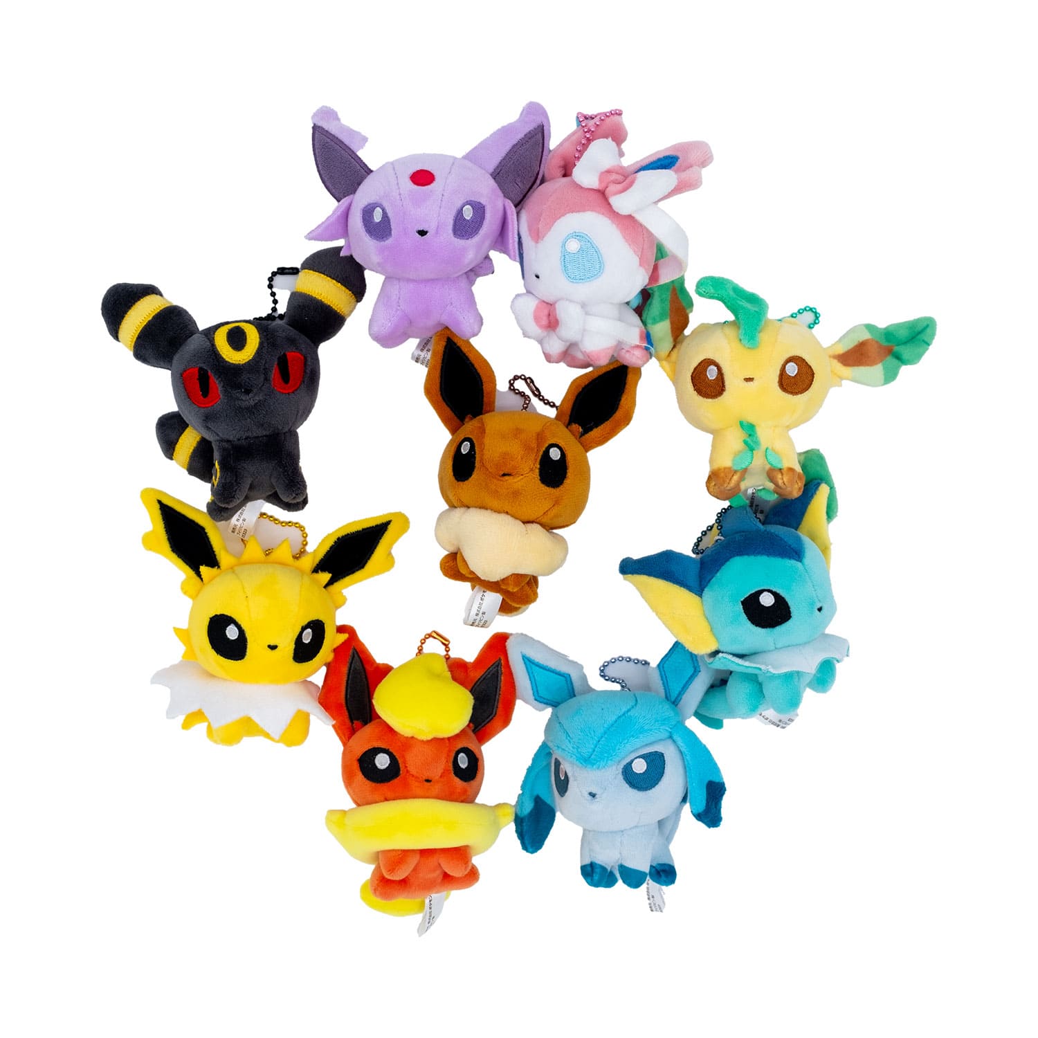 Alle 9 Eeveelutions als Plüschtiere in einem Kreis engeordnetmit Evoli in der Mitte. Alle sind frontal ausgerichtet.